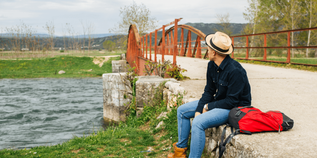 A man sitting on a bridge, enjoying the scenic view near Virginia Water Cars.