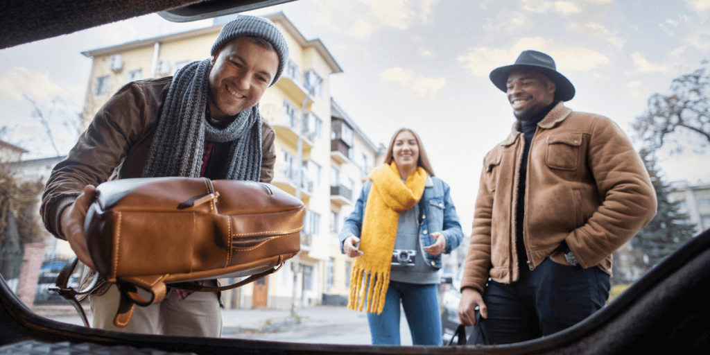 A group of friends loading their bags into a cab, preparing for a journey together with smiles and excitement.